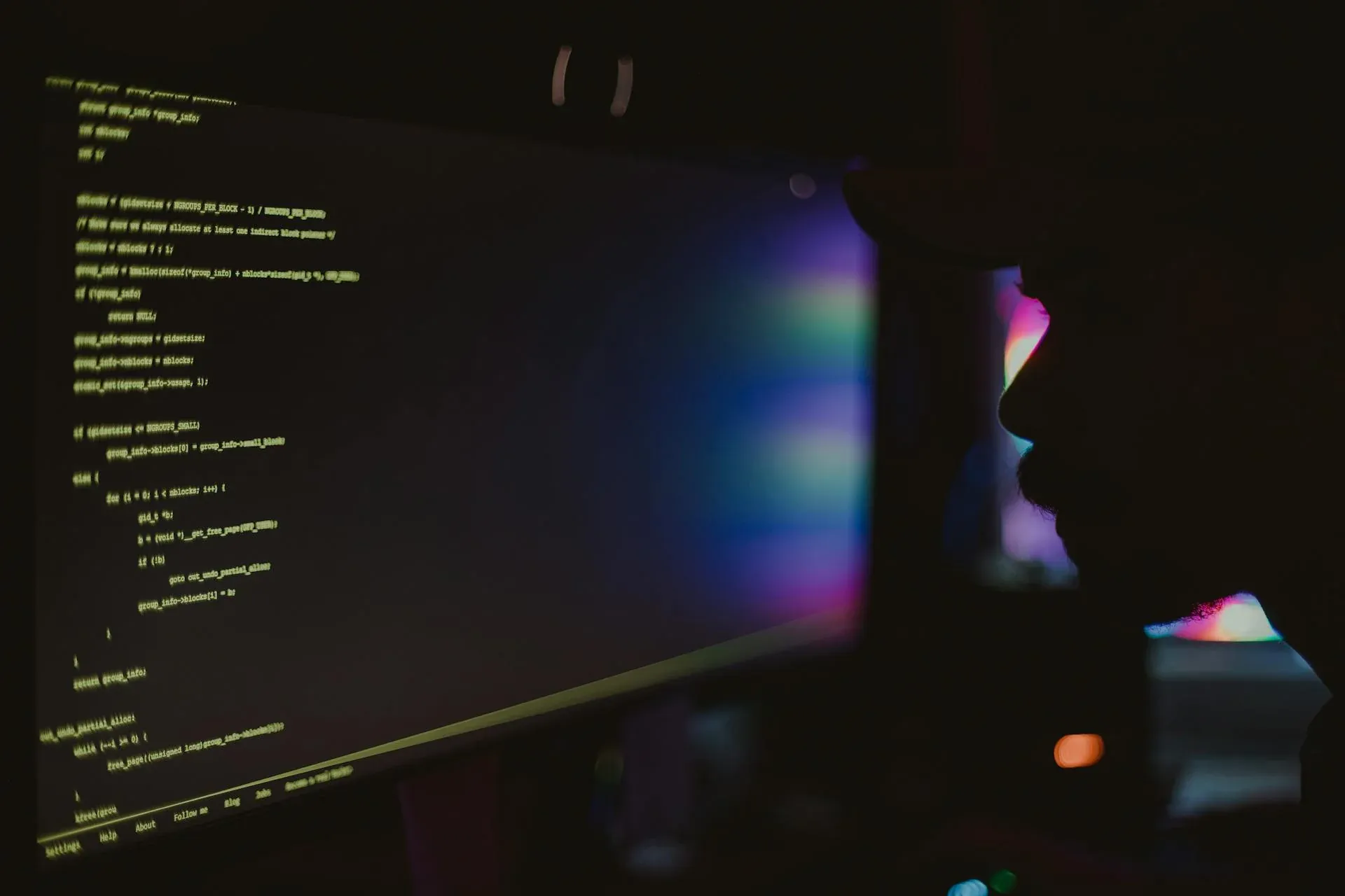 Silhouette of a developer coding in a dark room